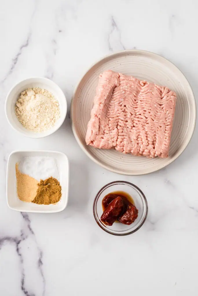 Ingredients to make chipotle chicken burgers on marble counter.