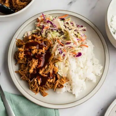 Plate full of instant pot bbq chicken thighs, rice and slaw.