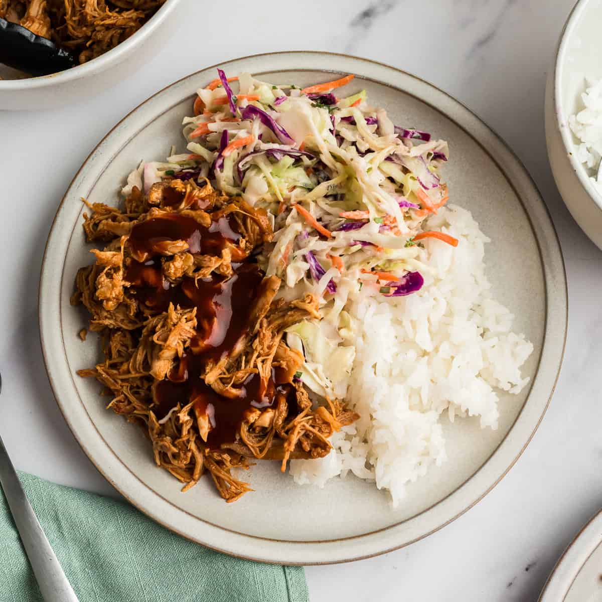 Plate full of instant pot bbq chicken thighs, rice and slaw.