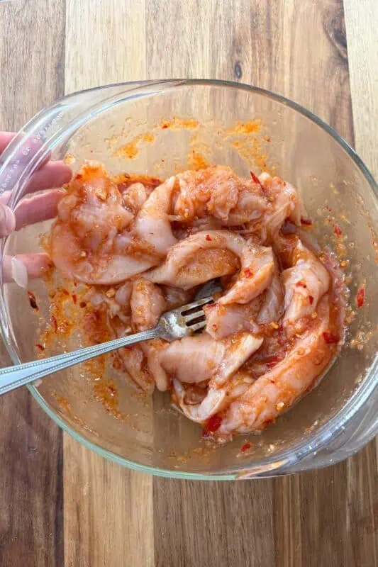 Chipotle pineapple marinade over chicken tenders in a glass bowl.