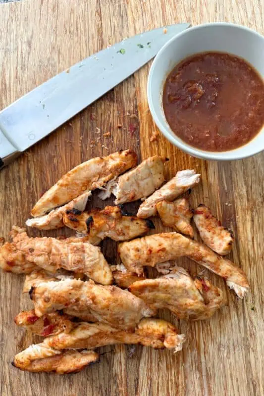 Pineapple chipotle chicken tenders on wood cutting board.