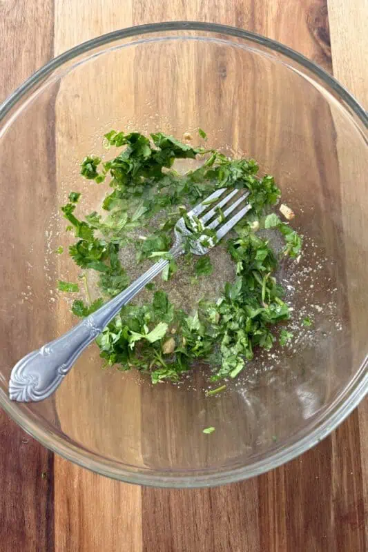 Glass bowl with dressing and chopped cilantro.