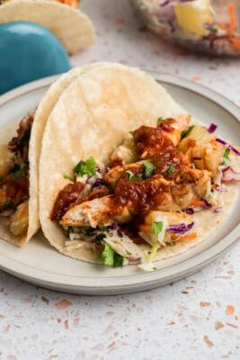 Pineapple chipotle chicken tacos on a white plate.