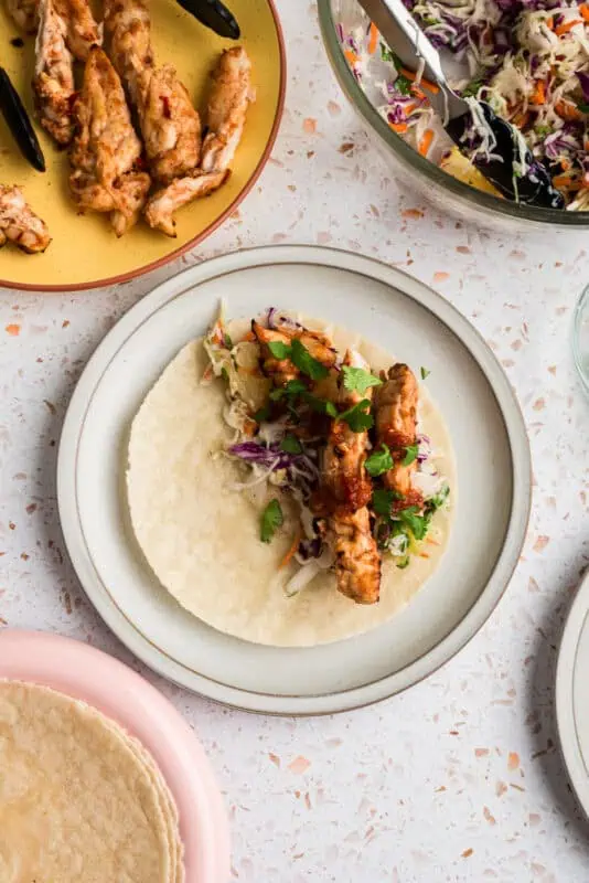 Single pineapple chipotle chicken taco on white plate