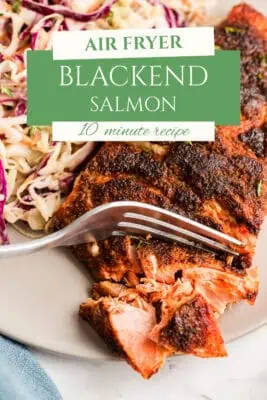 Fork flaking blackened salmon on a plate