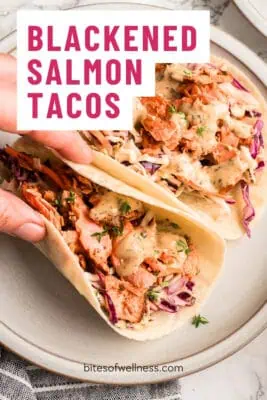 Hand picking up a blackened salmon taco.