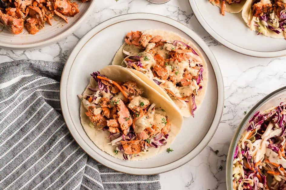 Two blackened salmon tacos on a white plate.