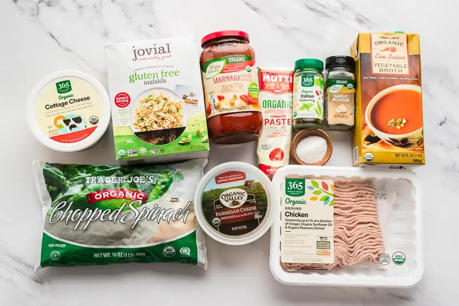 Ingredients to make chicken lasagna soup on marble countertop.