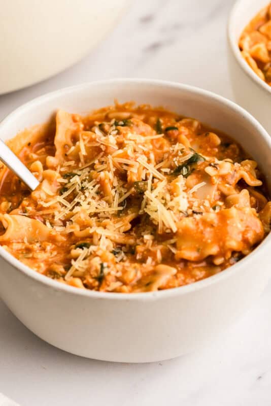 White bowl filled with lasagna soup, spoon resting in the bowl.