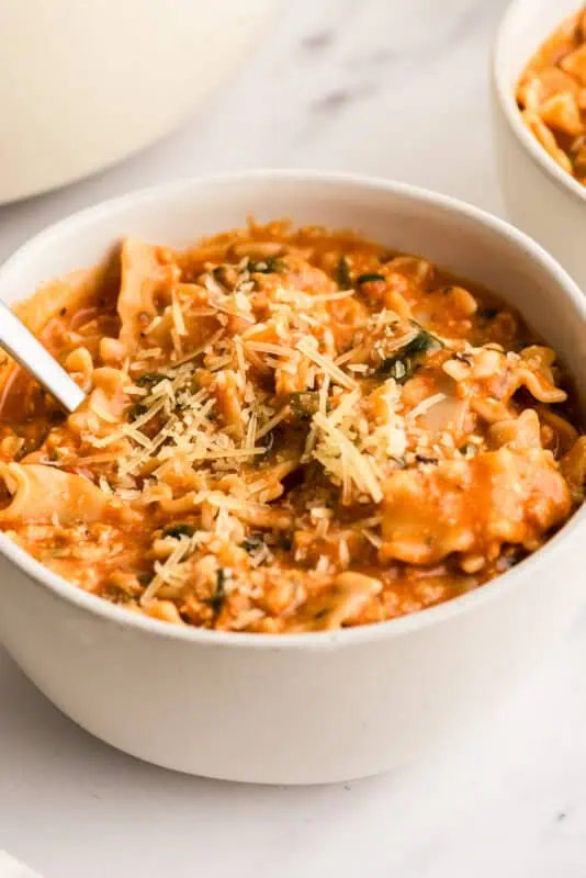 White bowl filled with lasagna soup, spoon resting in the bowl.