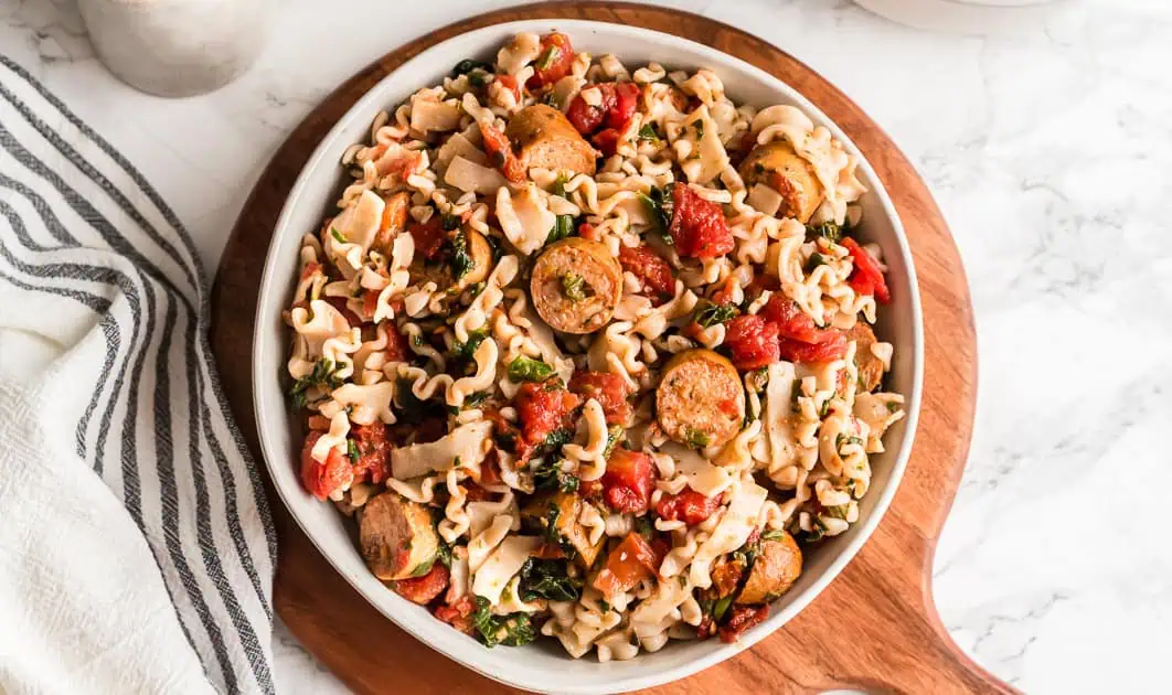 Large bowl of italian chicken sausage pasta on a wood board.