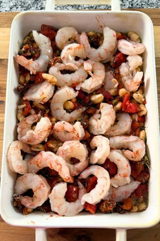 Shrimp added to the top of the tomato mixture in casserole dish.