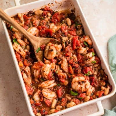 Casserole dish filled with Mediterranean Shrimp, spoon resting in the dish.