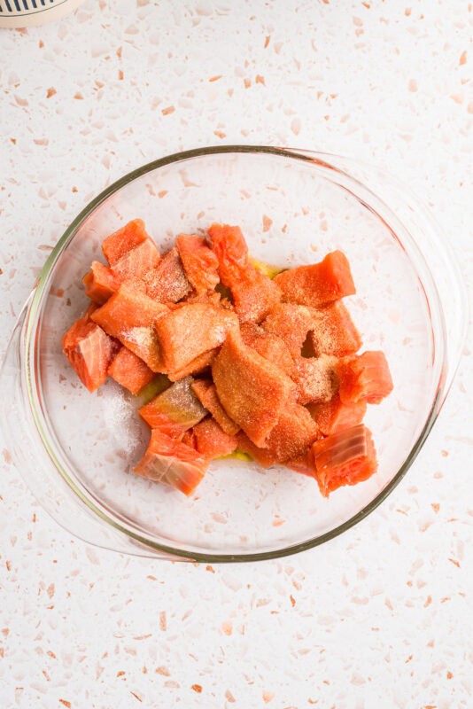 Salmon cut into cubes in a glass bowl.