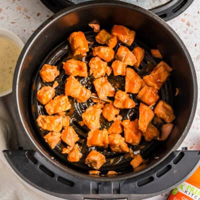 Buffalo salmon bites in an air fryer basket.