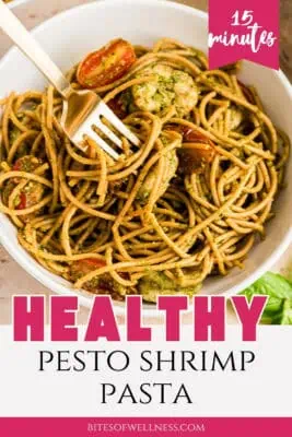 Fork resting in a bowl of pesto shrimp pasta.