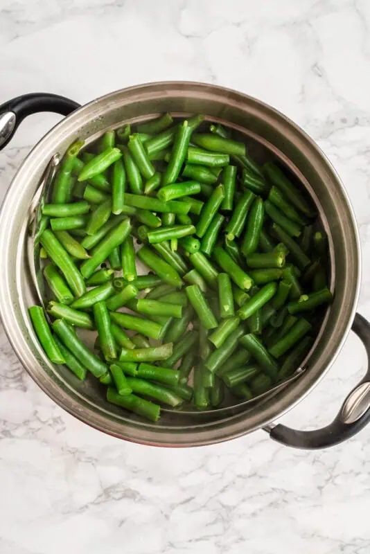Green beans in boiling water in a pot.