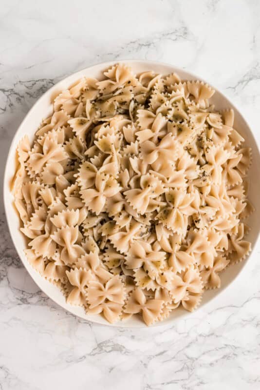Large white bowl filled with cooked bow tie pasta.