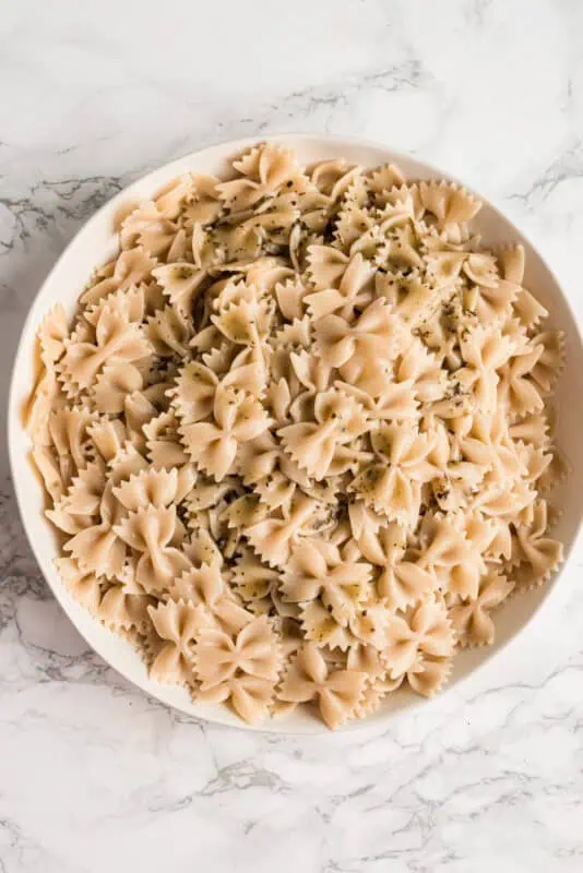 Large white bowl filled with cooked bow tie pasta.