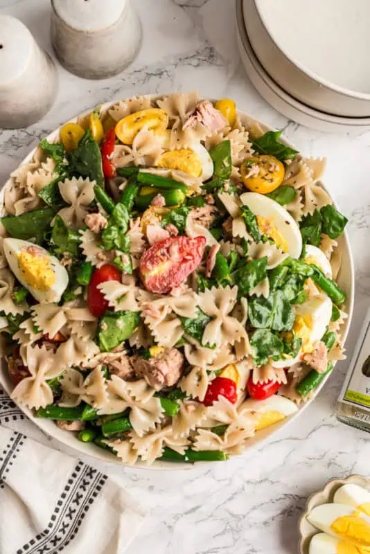 Niçoise tuna pasta salad in a white bowl after tossing the ingredients together.