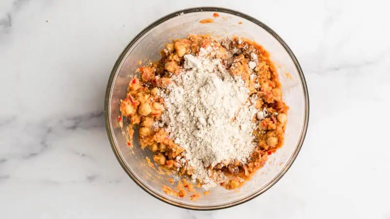 Oat flour added to large glass bowl with chickpea mixture.