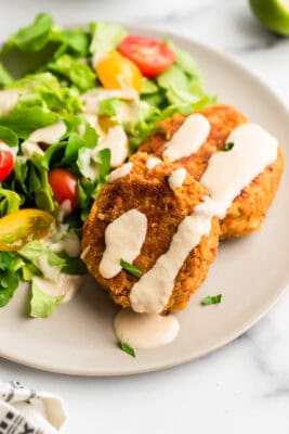 Tahini sauce drizzled over chickpea fritters on plate.