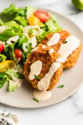 Tahini sauce drizzled over chickpea fritters on plate.