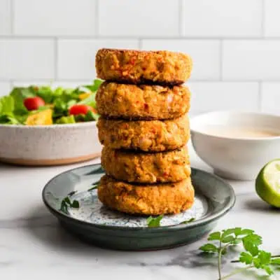 Chickpea fritters stacked on top of each other (5 high) on blue plate.