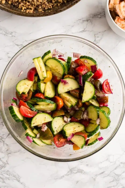Glass bowl filled with cucumber tomato salad.