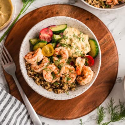 Bowl filled with shrimp, quinoa and a cucumber tomato salad.