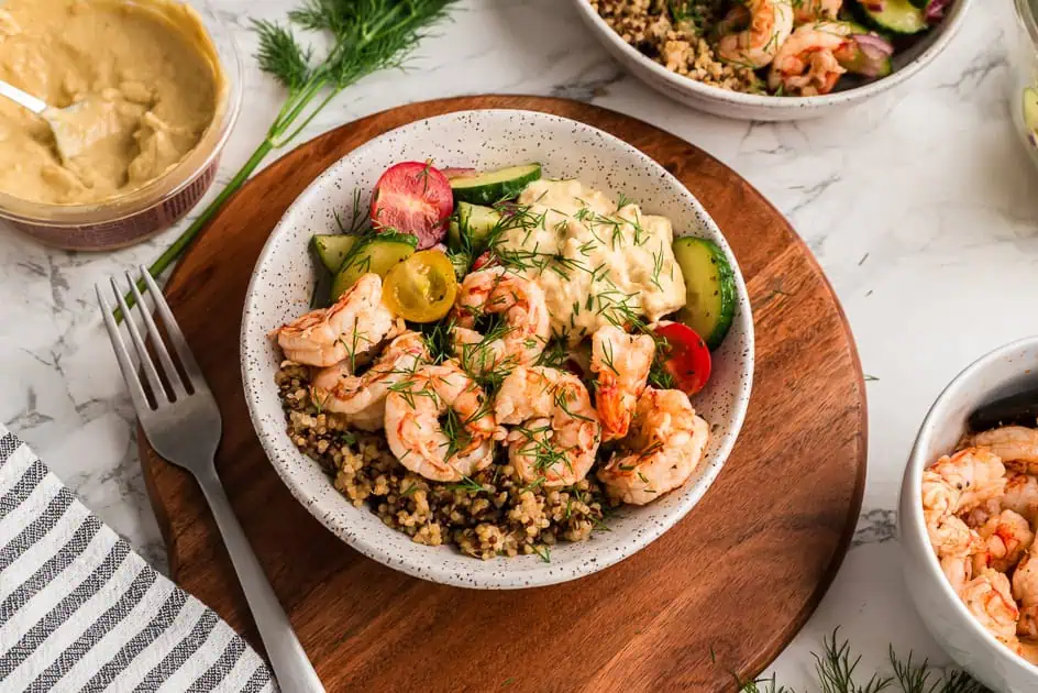 Greek shrimp bowl with a cucumber tomato salad on a wooden bowl.
