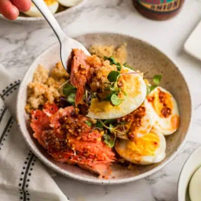 Forkful of smoked salmon, quinoa and eggs being lifted from bowl.
